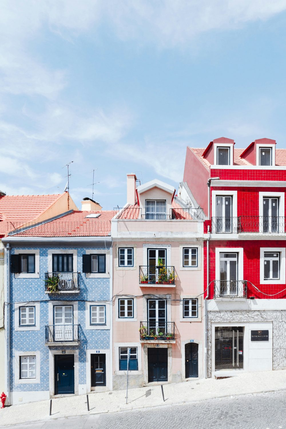 Steep sunny street with colourful town houses against a blue sky