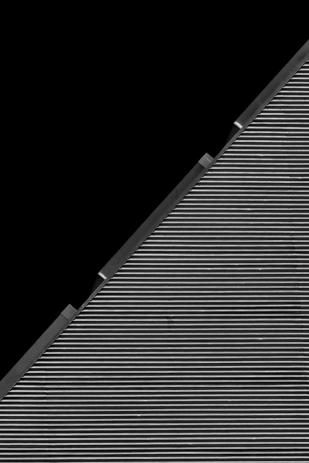 Geometric view of diagonal section of roof with metal corrugations against black background 