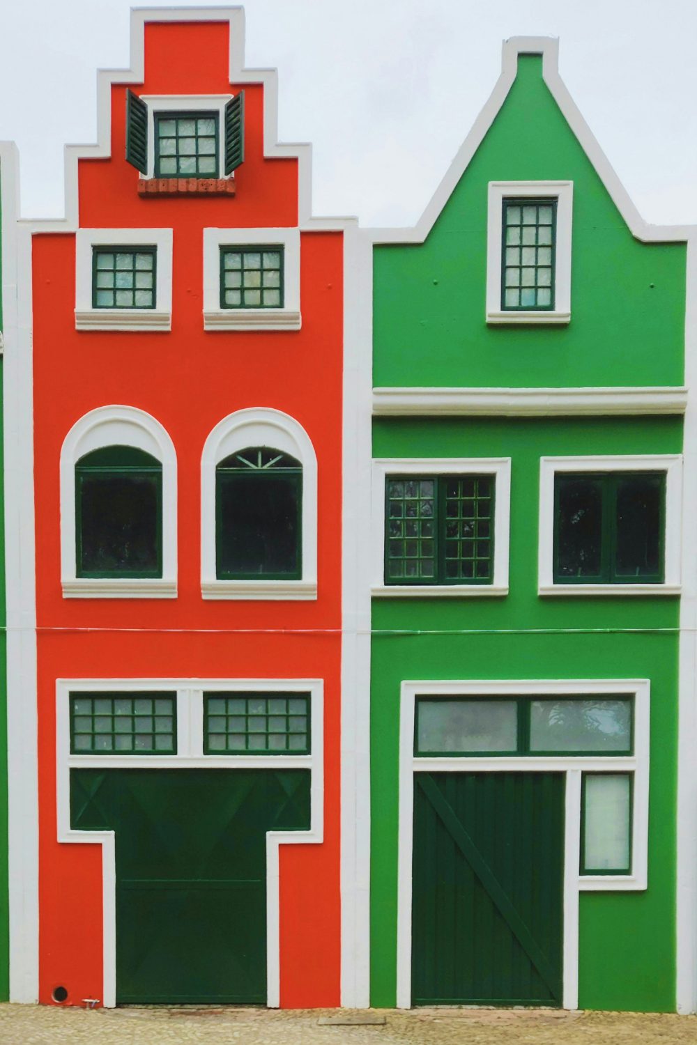 Bright orange and green houses with white trim and dark garage doors