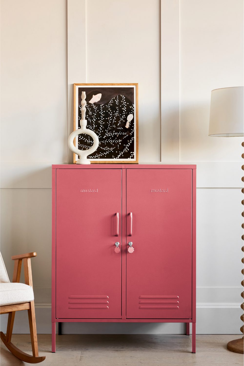 White panelled living room with pink cupboard, white rocking chair and white lamp