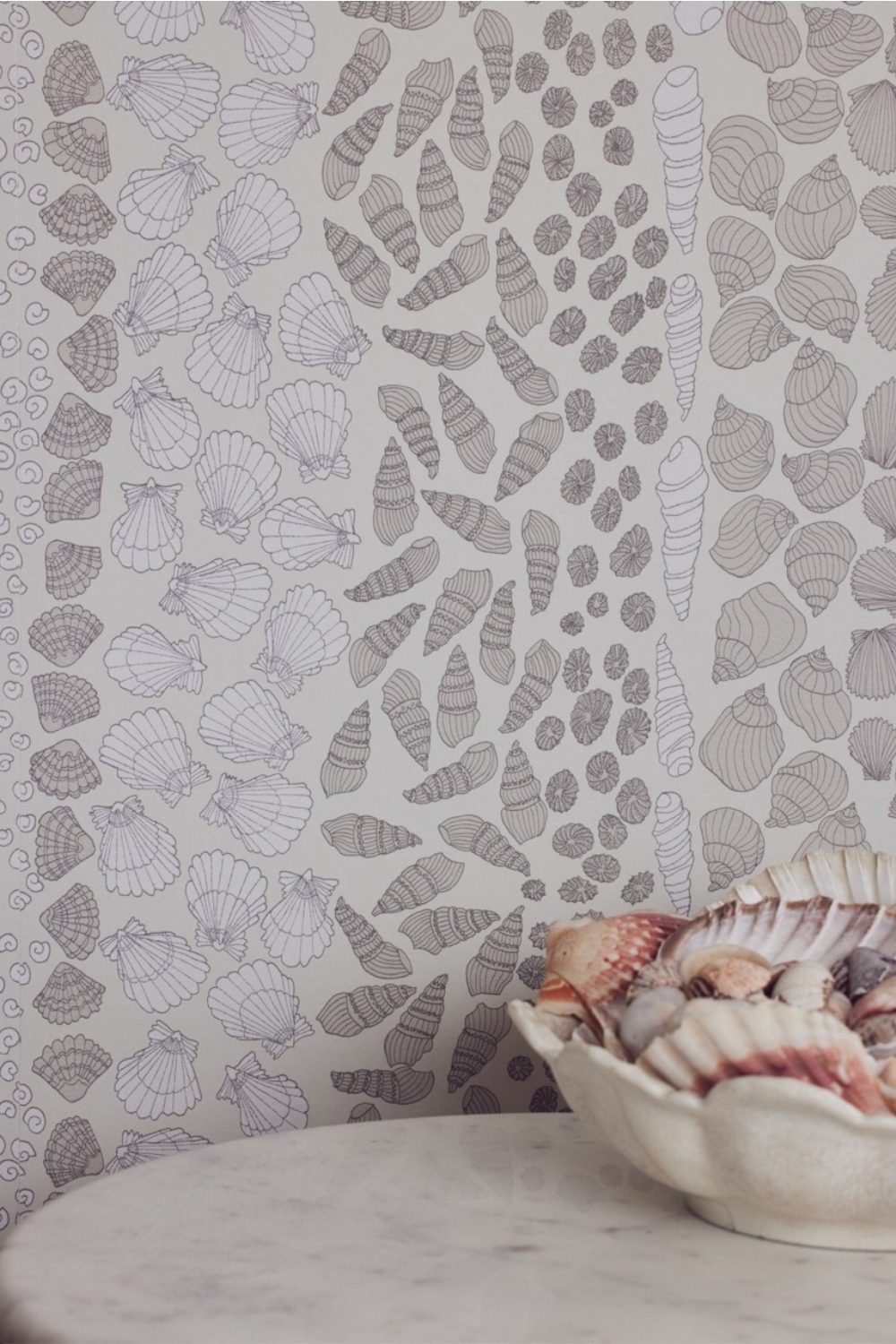 Shell motif wallpaper next to bowl of shells on white table