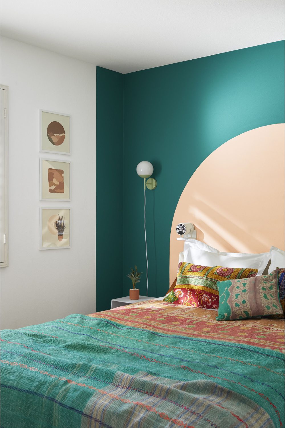 Bed with patterned cushions and blanket against a turquoise and peach feature wall