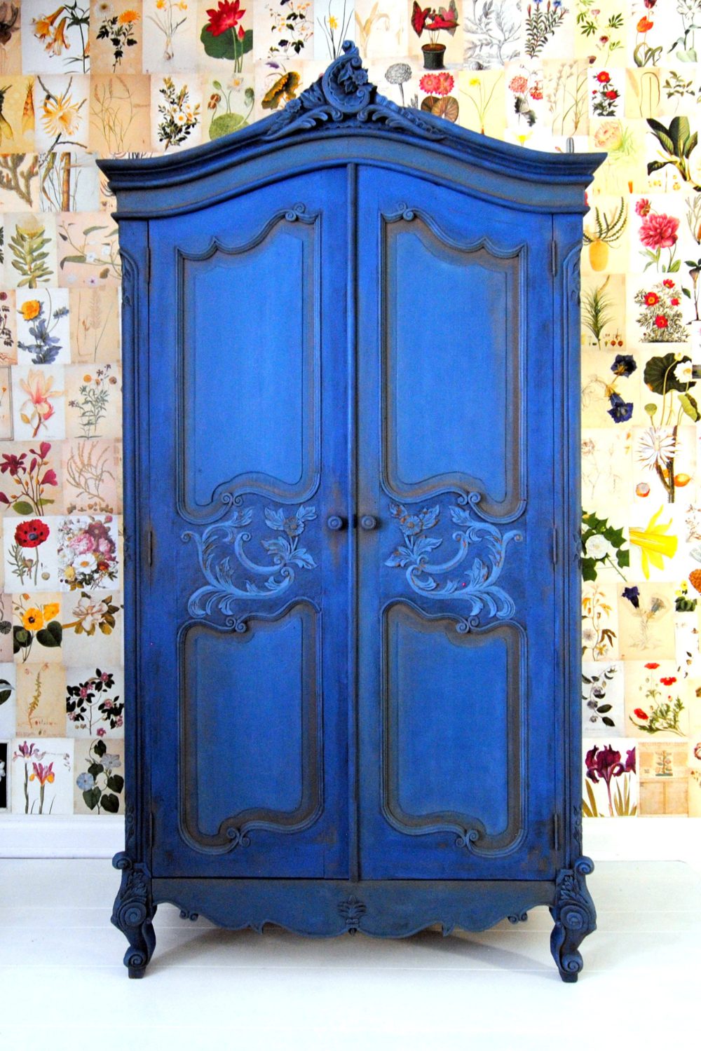 Freestanding blue wardrobe against flower-patterned wallpaper