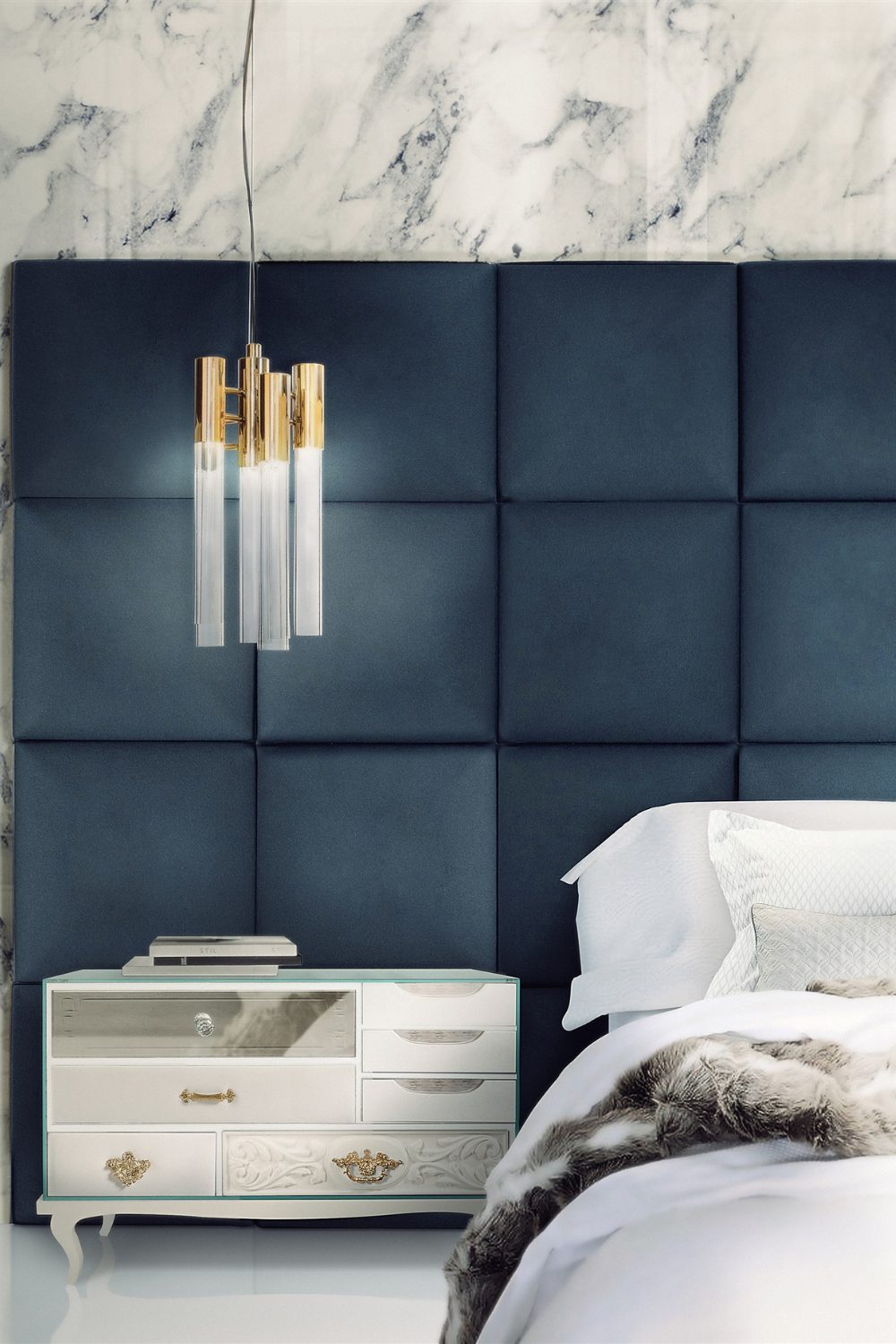 White bed with large navy padded headboard, white bedside table and gold hanging lamp