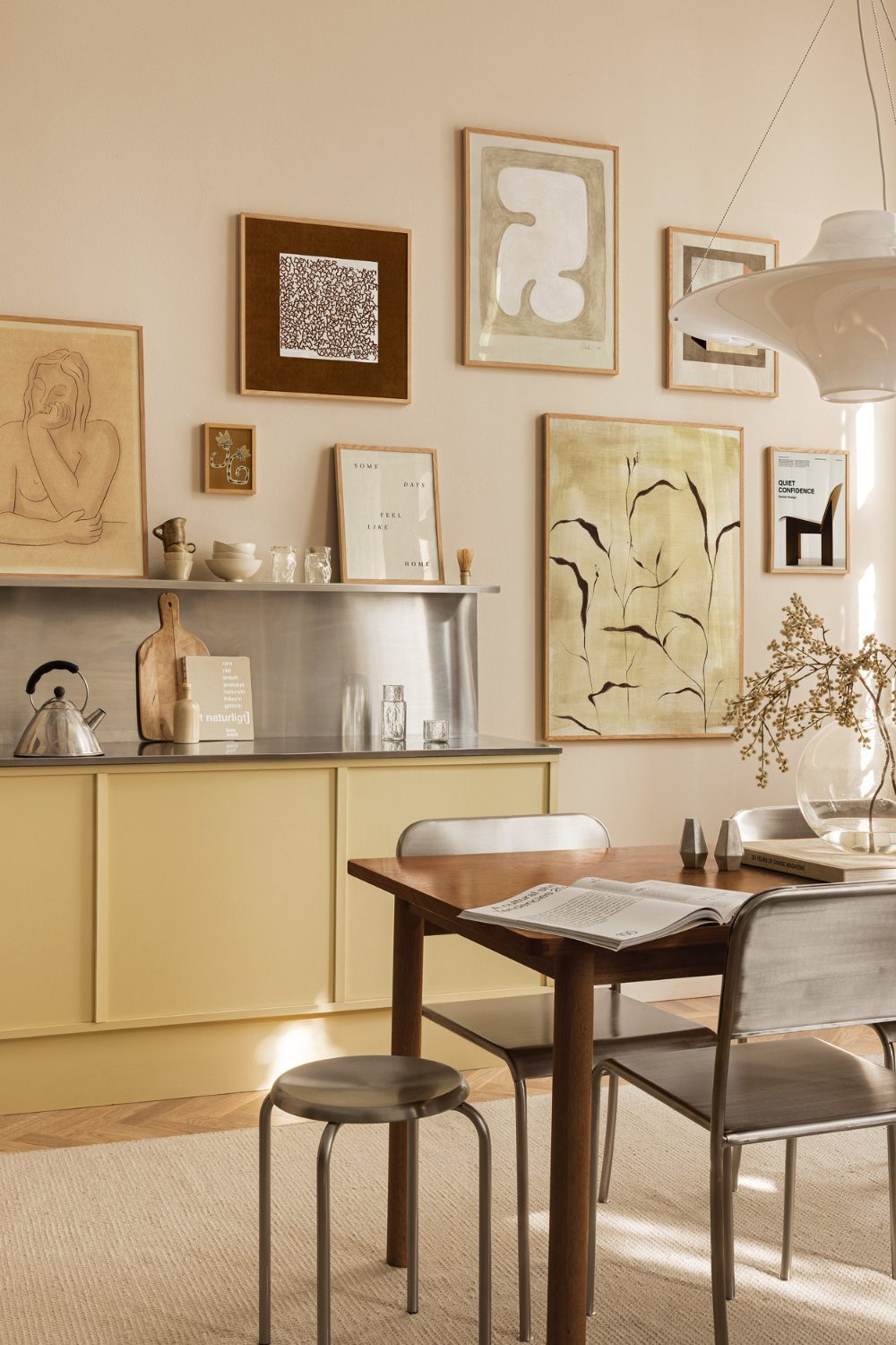 Kitchen with yellow cabinets, wooden table and metal chairs, high ceilings and yellow gallery wall