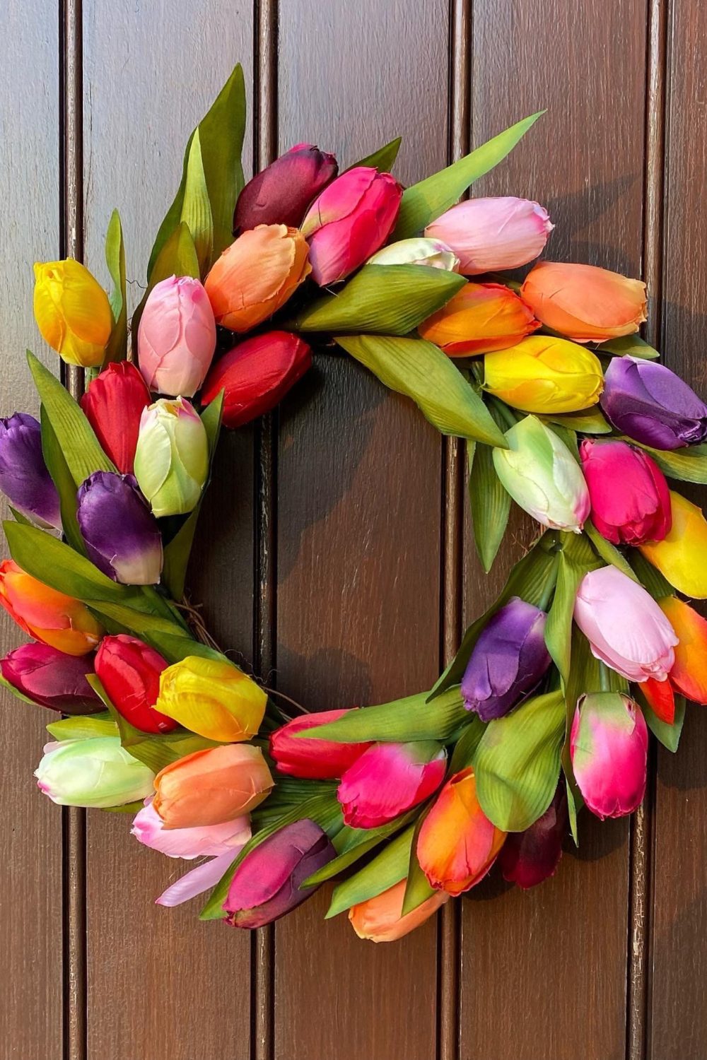 Wreath made of colourful tulips on a dark wood door