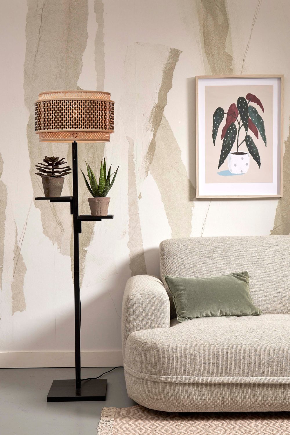 White sofa next to framed print of pot plant and standing lamp with shelving attachments holding pot plants