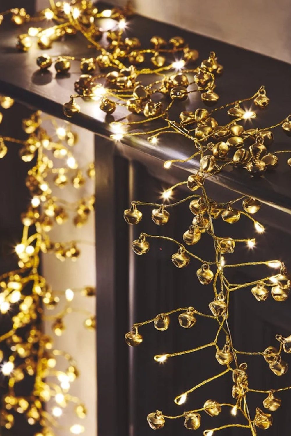 Gold string of bells and lights hanging over a dark banister