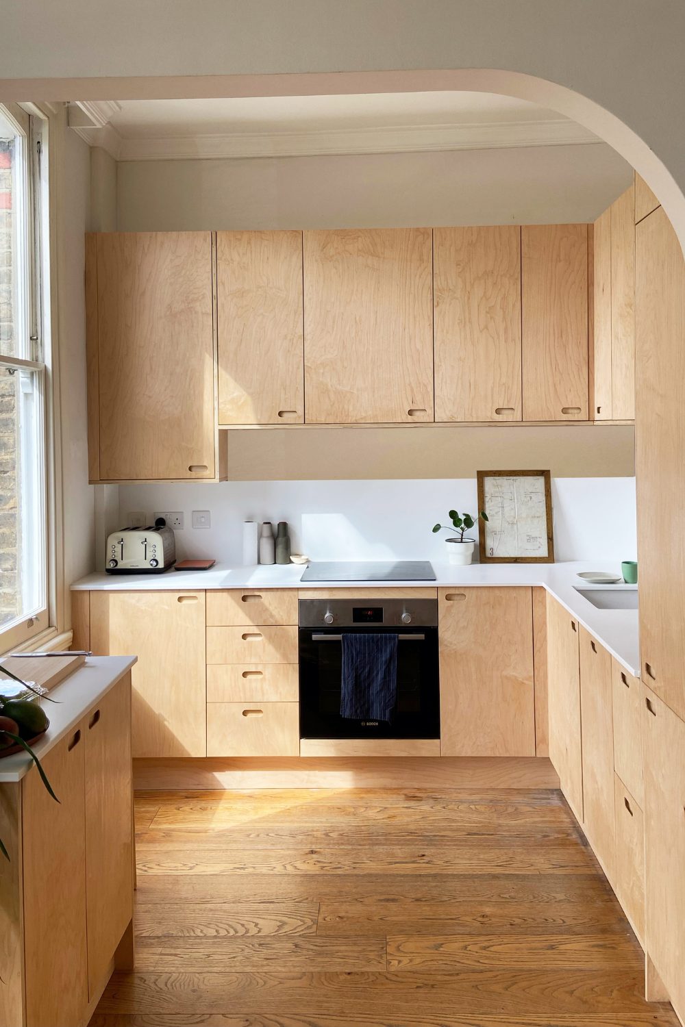 White kitchen with wooden cabinets, electric hob and wooden floor