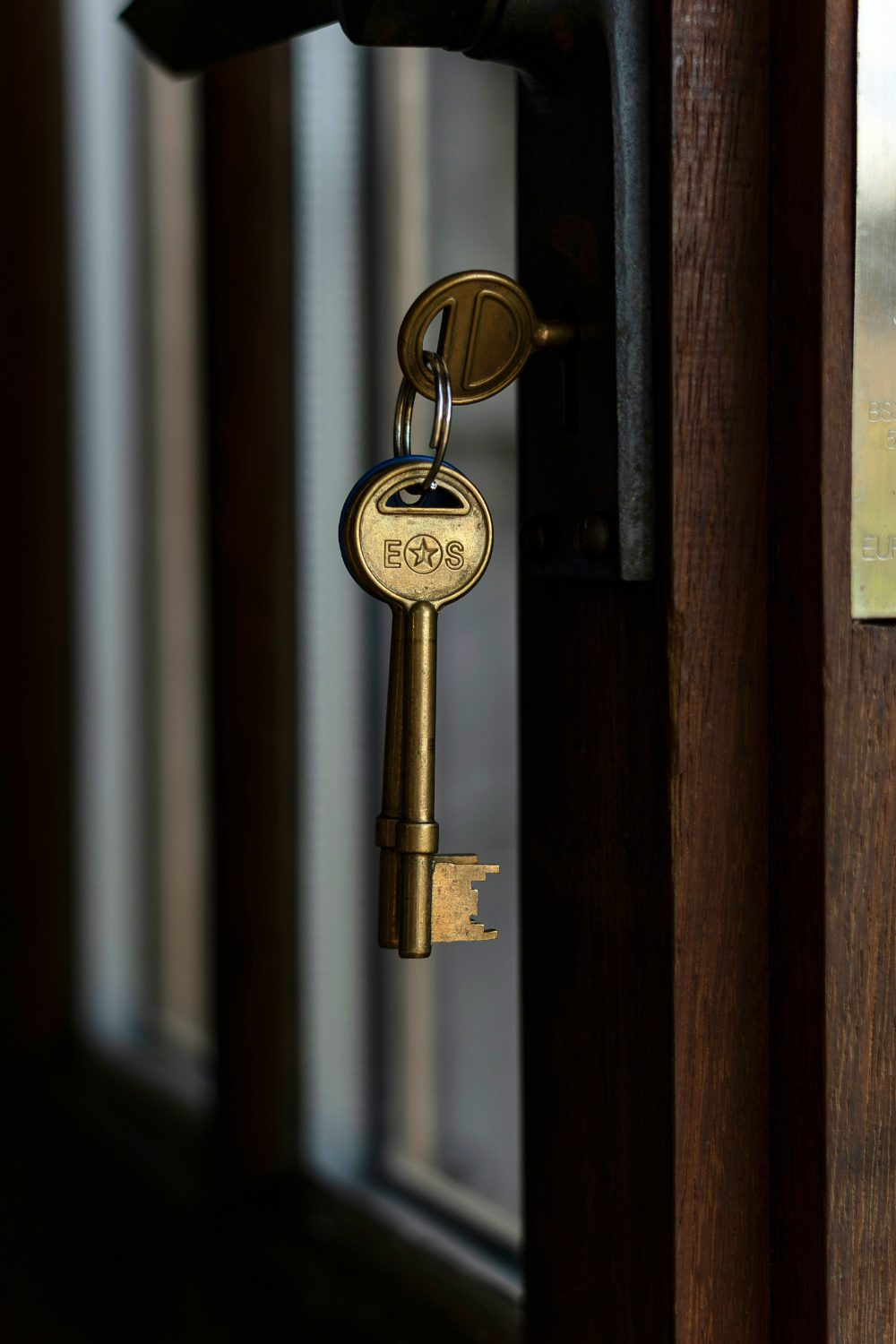 Gold keys hanging from dark wooden door