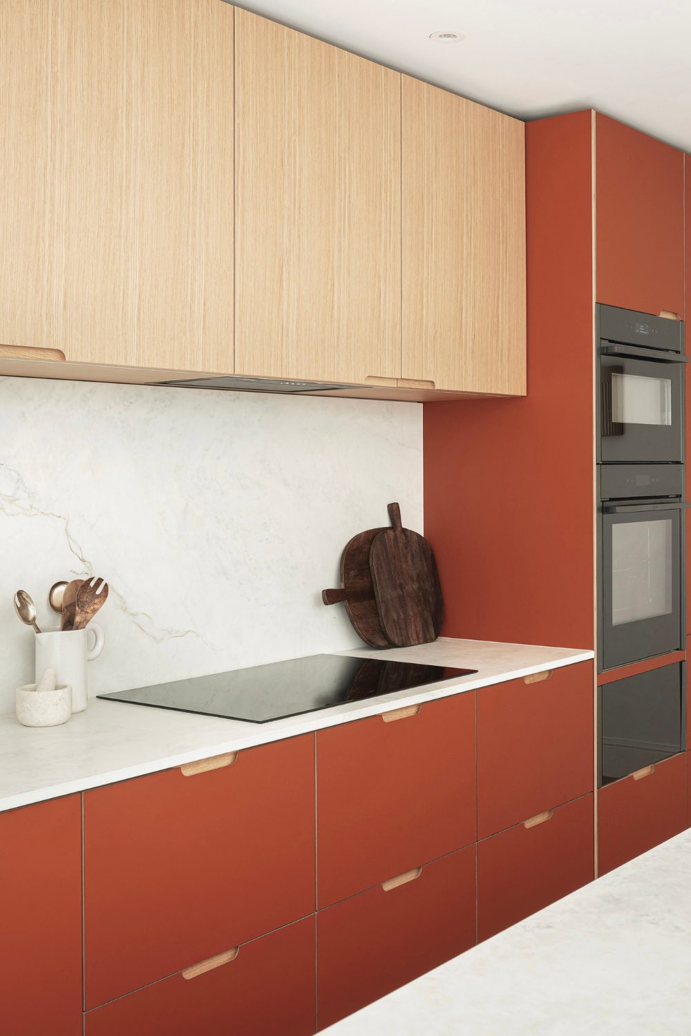 Kitchen with electric hob, white marble counter and red cabinets