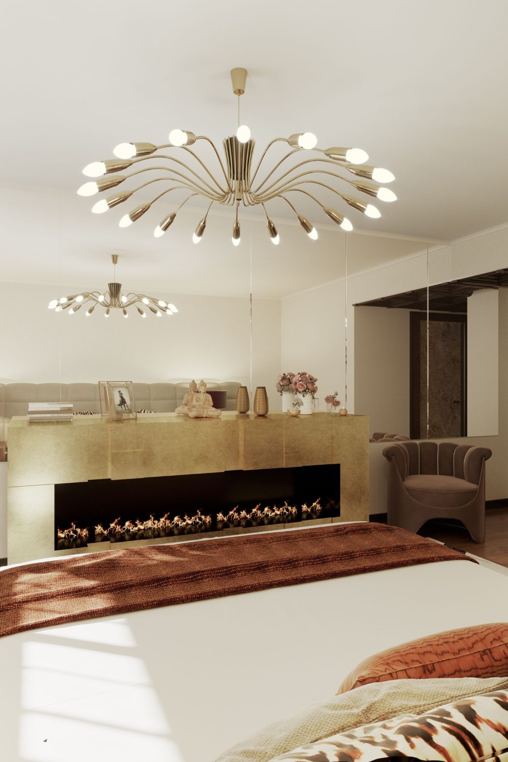 Bed with brown throw and cushions in front of mirror wall, fireplace and brown armchair under gold light fixture