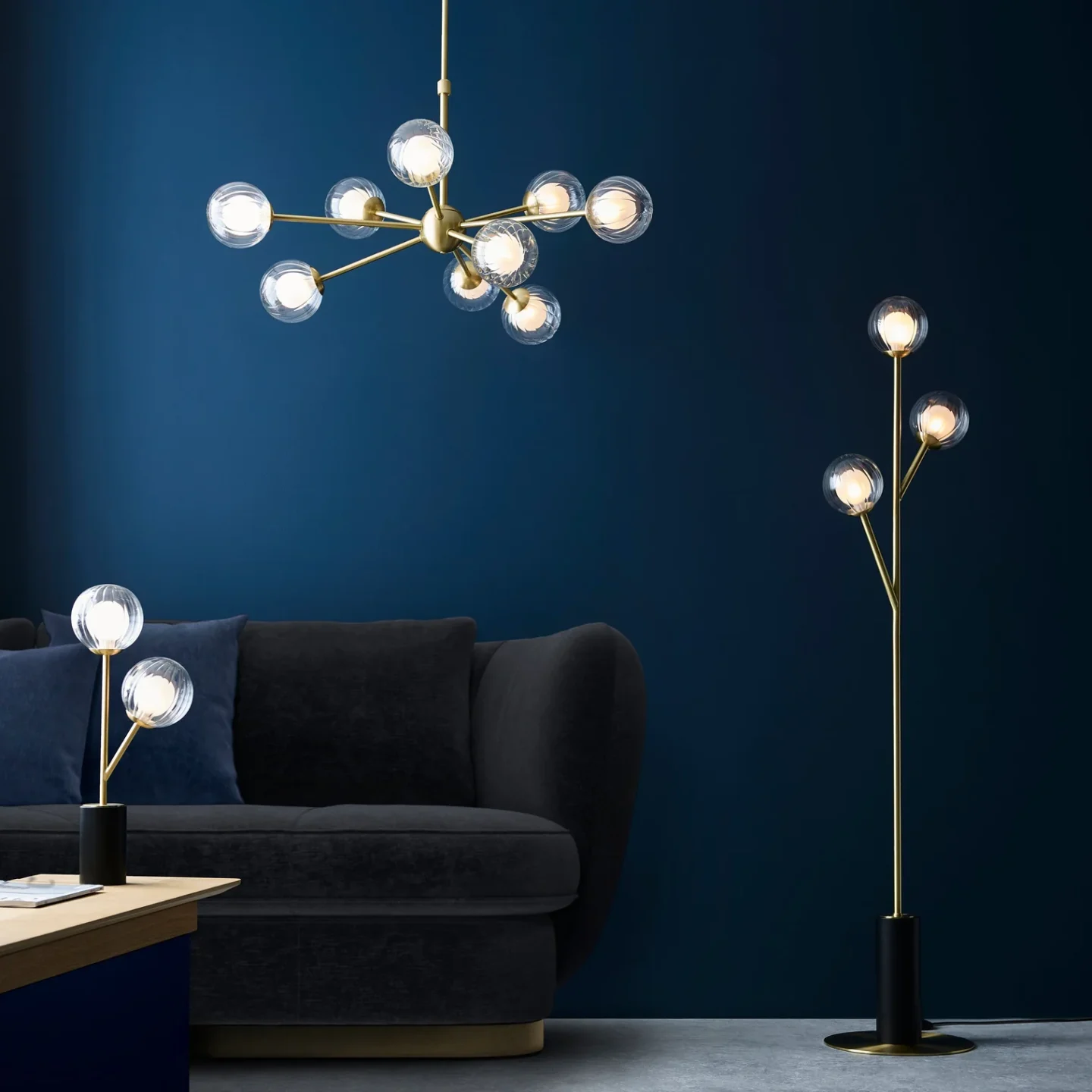 Gold standing lamps and overhead light in blue room with black sofa