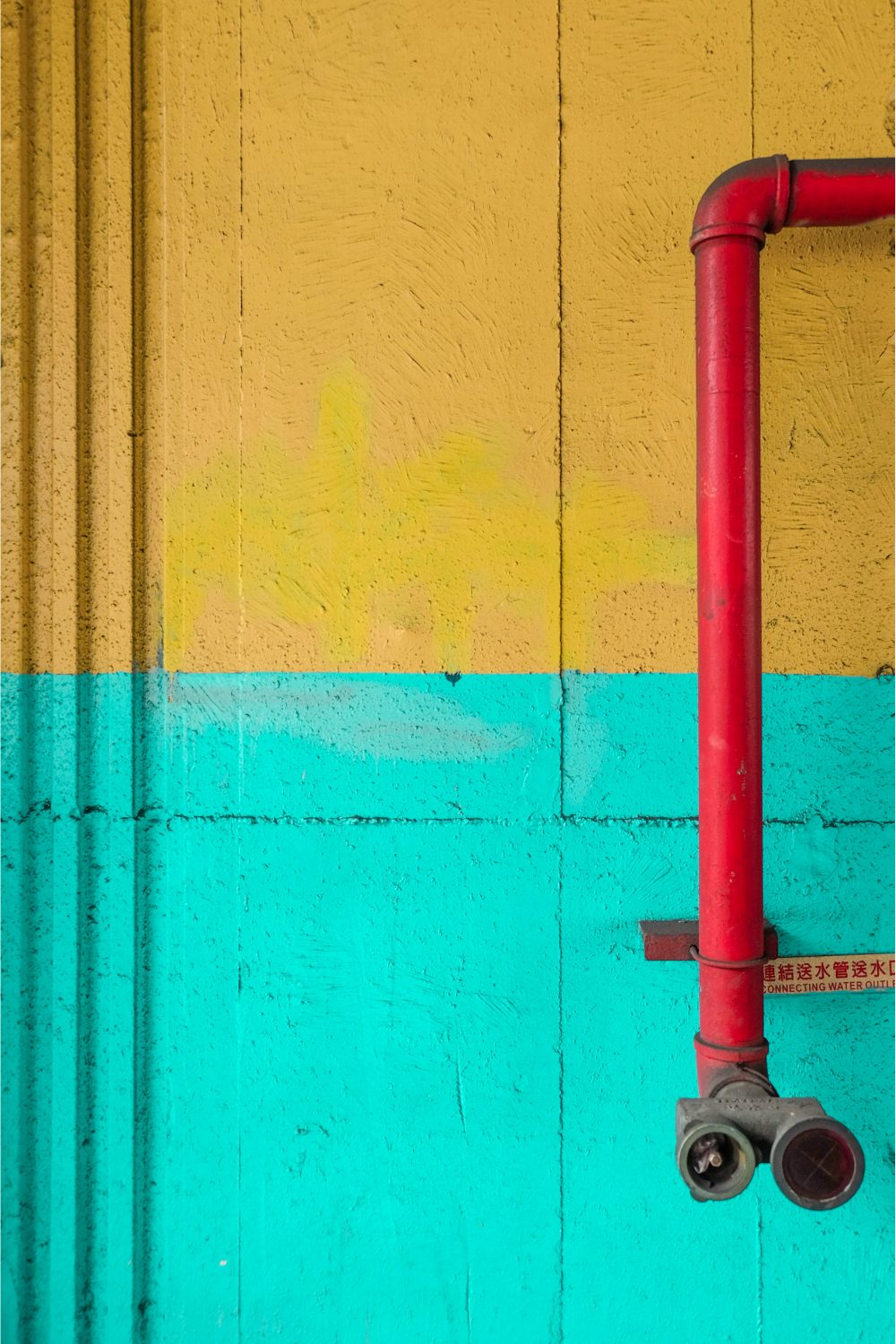 Red pipe on bright yellow and blue wall