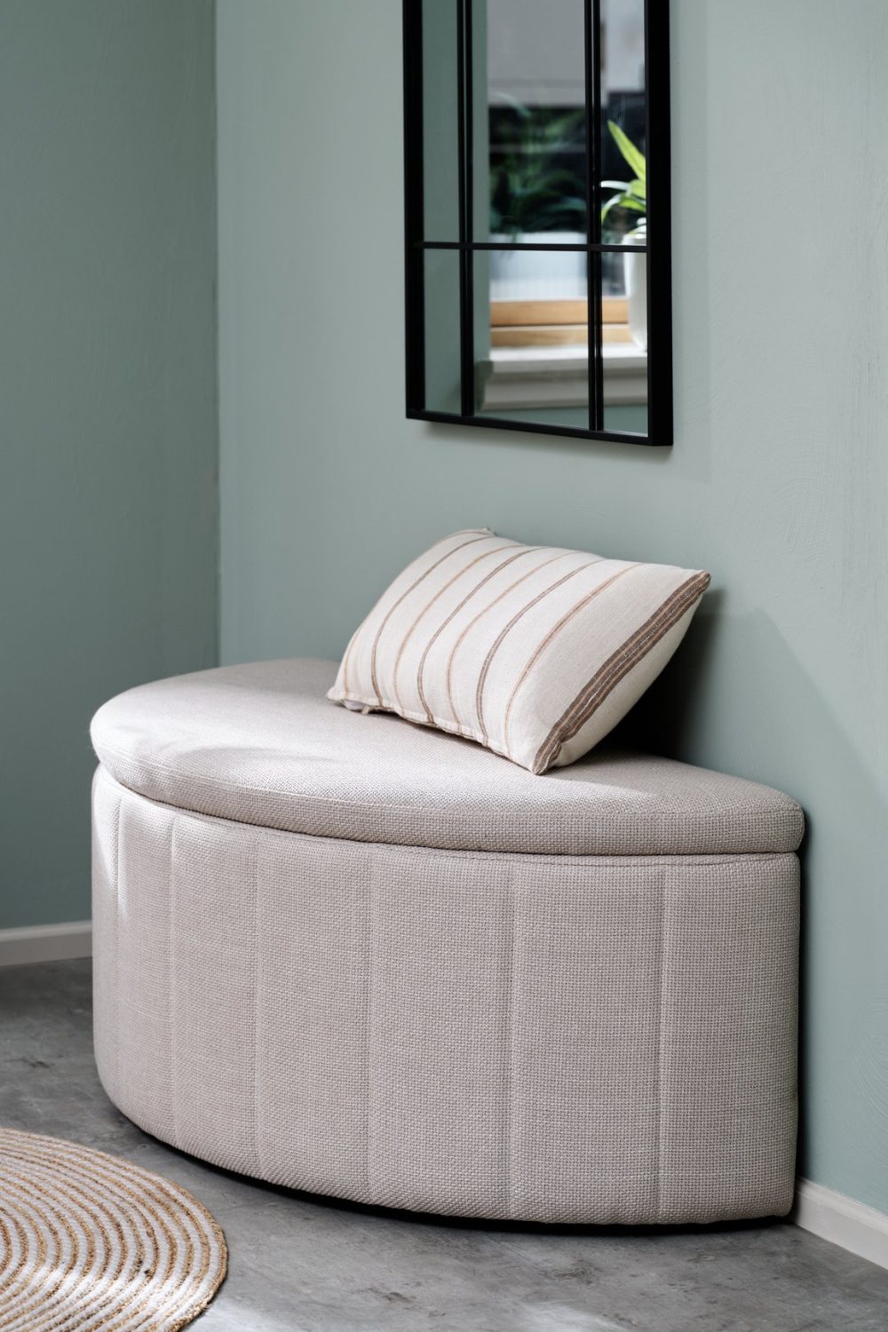 Curved white bench against grey-blue wall below black-framed mirror