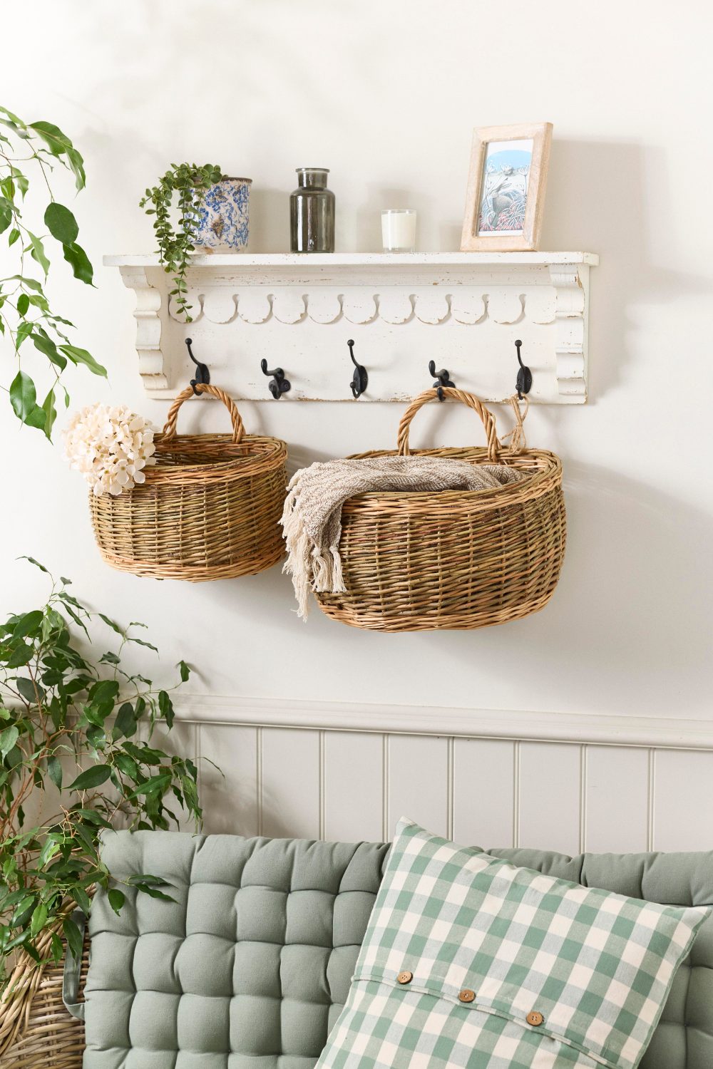 Wicker baskets hanging on hooks on white wall above green seat
