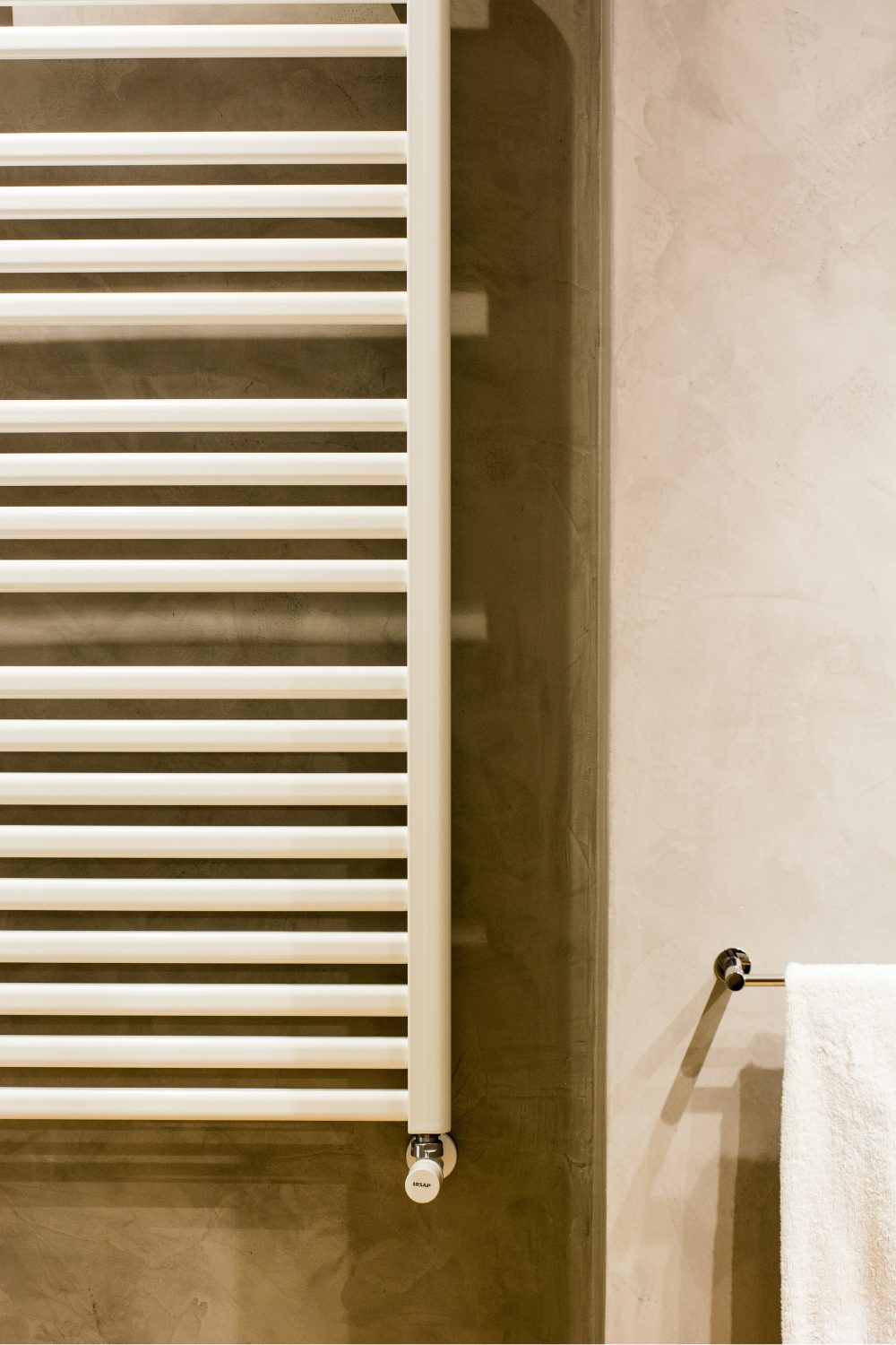 Neutral-coloured bathroom with wall-mounted white radiator and towel rail
