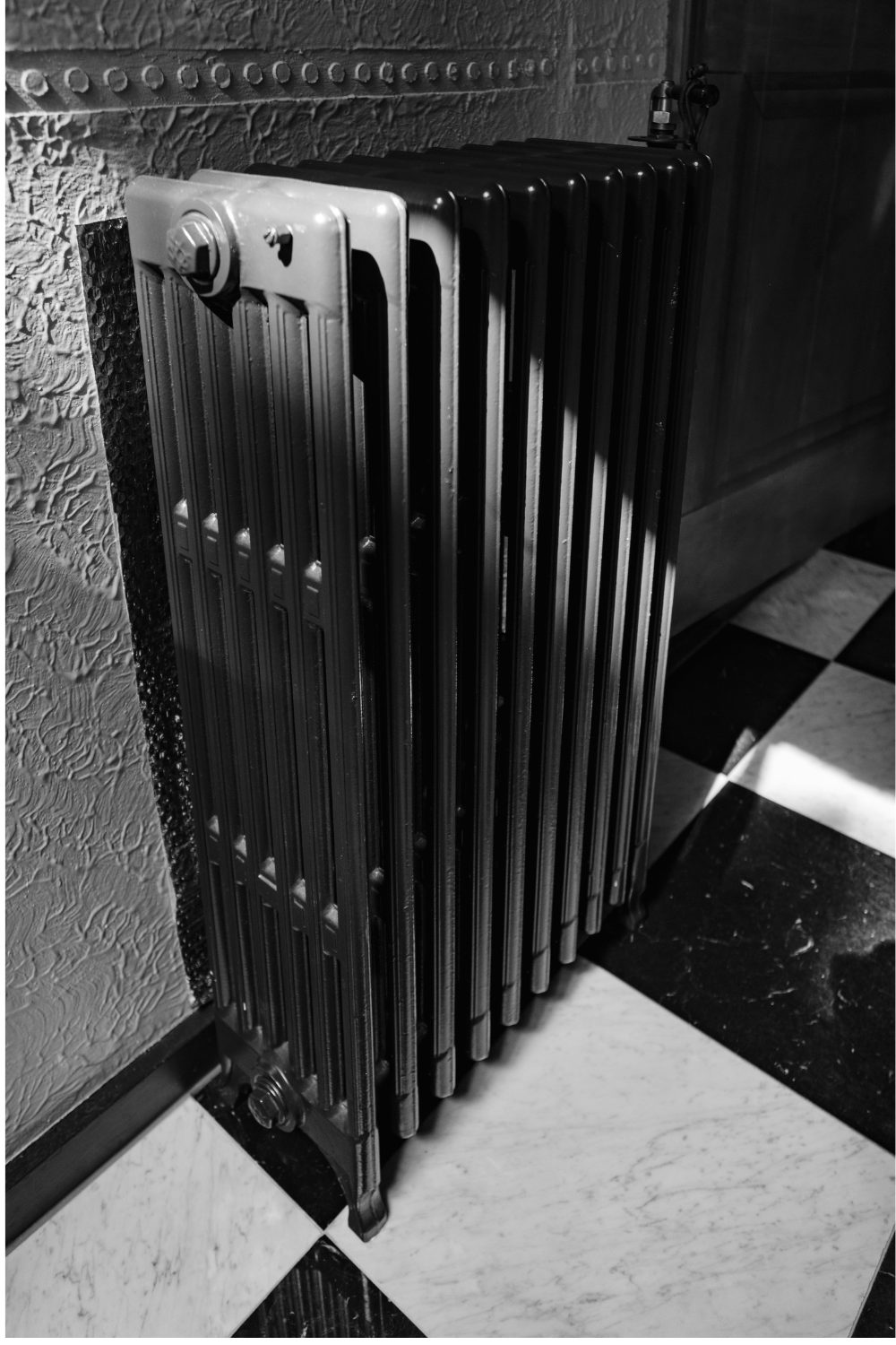Black radiator on black and white tiled floor