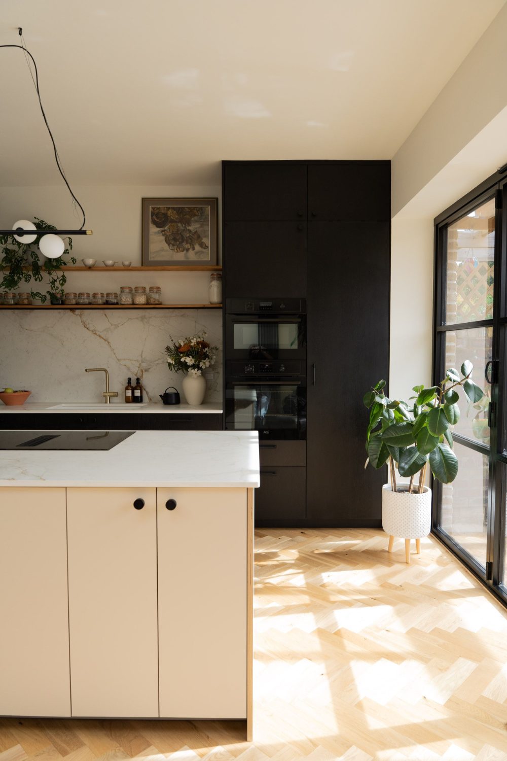 Kitchen with parquet wood floor, black cabinet, white marble backsplash and white island