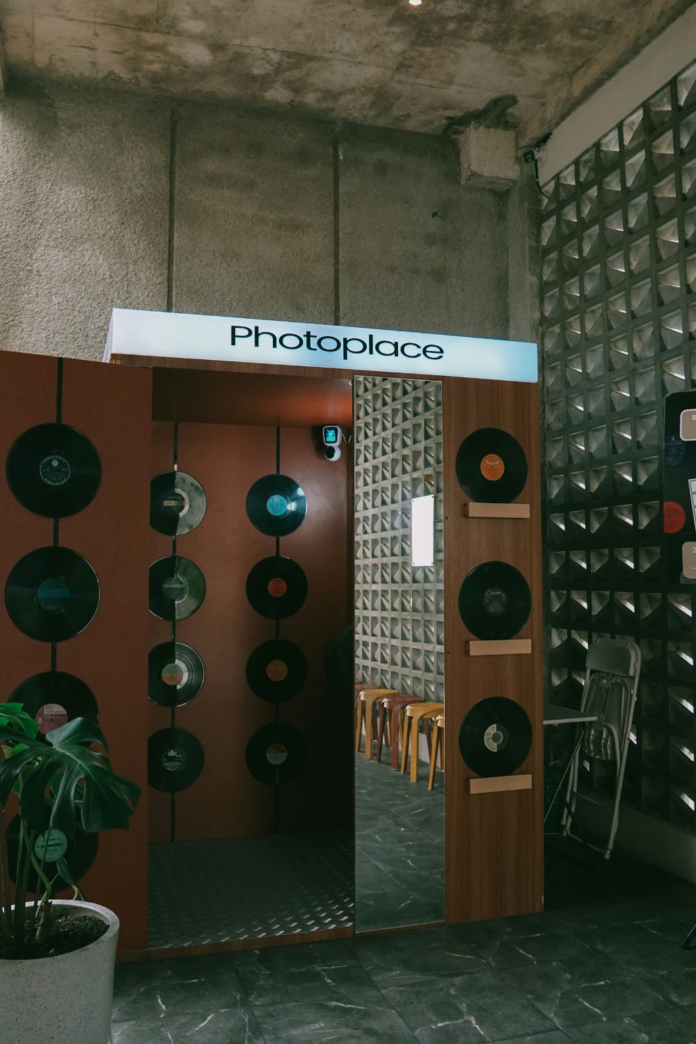 Photo booth entrance in industrial space with glass and concrete walls, with red doors lined with vinyl records