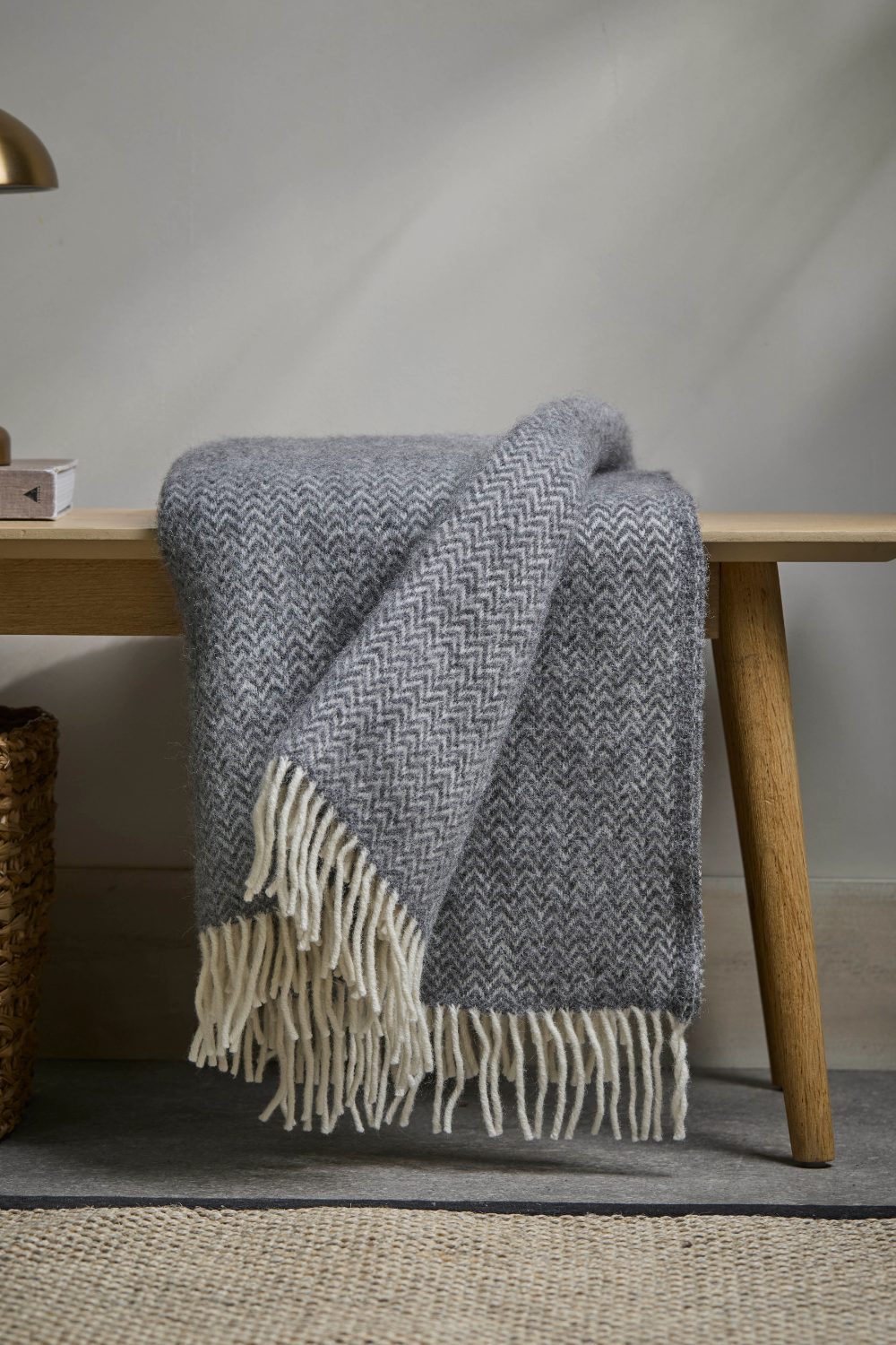 Grey chevron woollen throw draped over wooden bench on grey rug