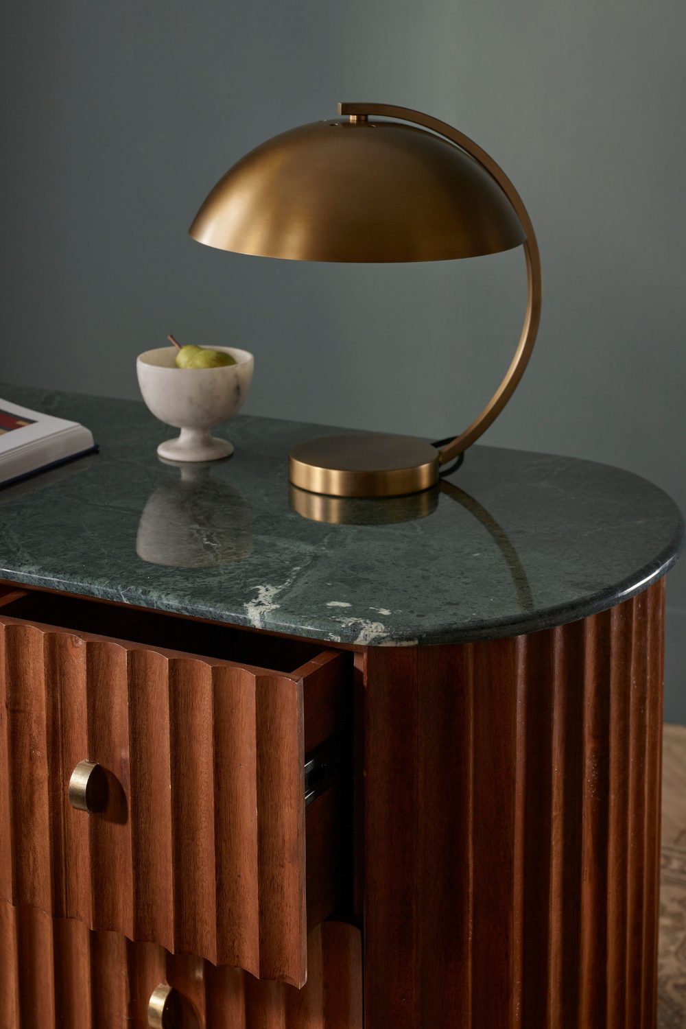 Curved gold lamp on a wood and stone cabinet