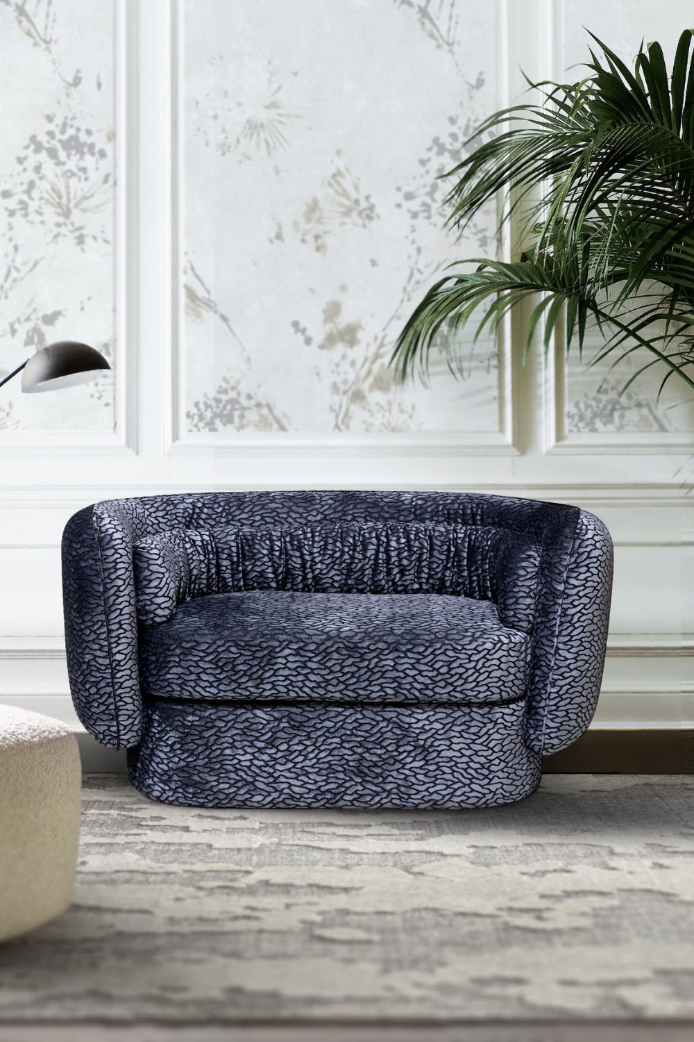 Blue patterned armchair on grey rug in white room with framed white botanical prints and potted plant