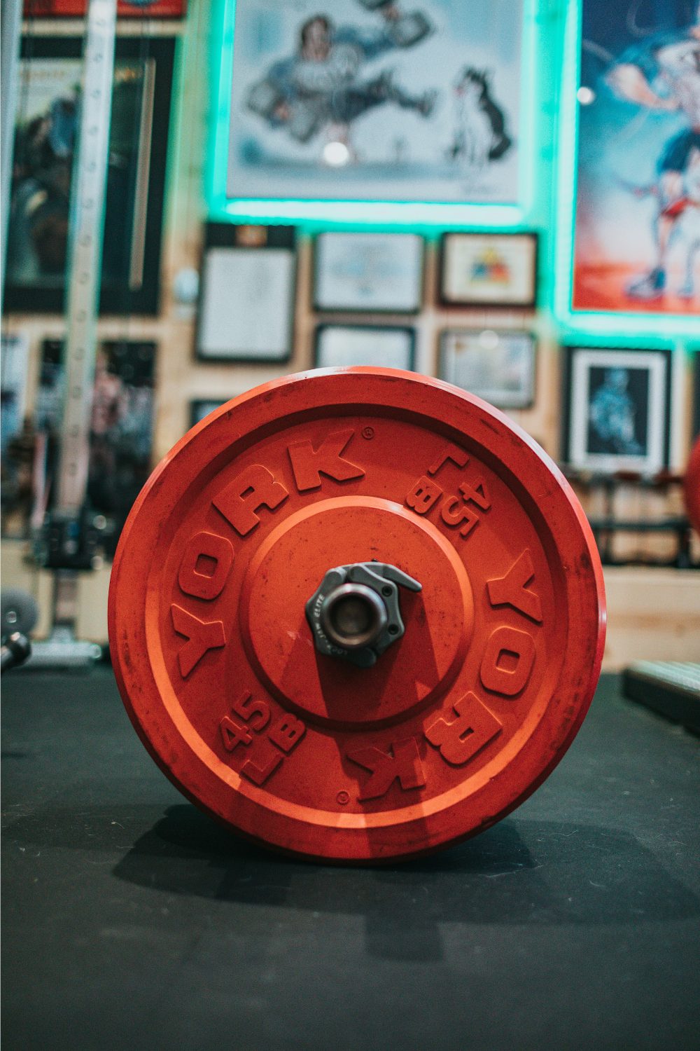 Red weight on black exercise mat with wall of framed pictures in background