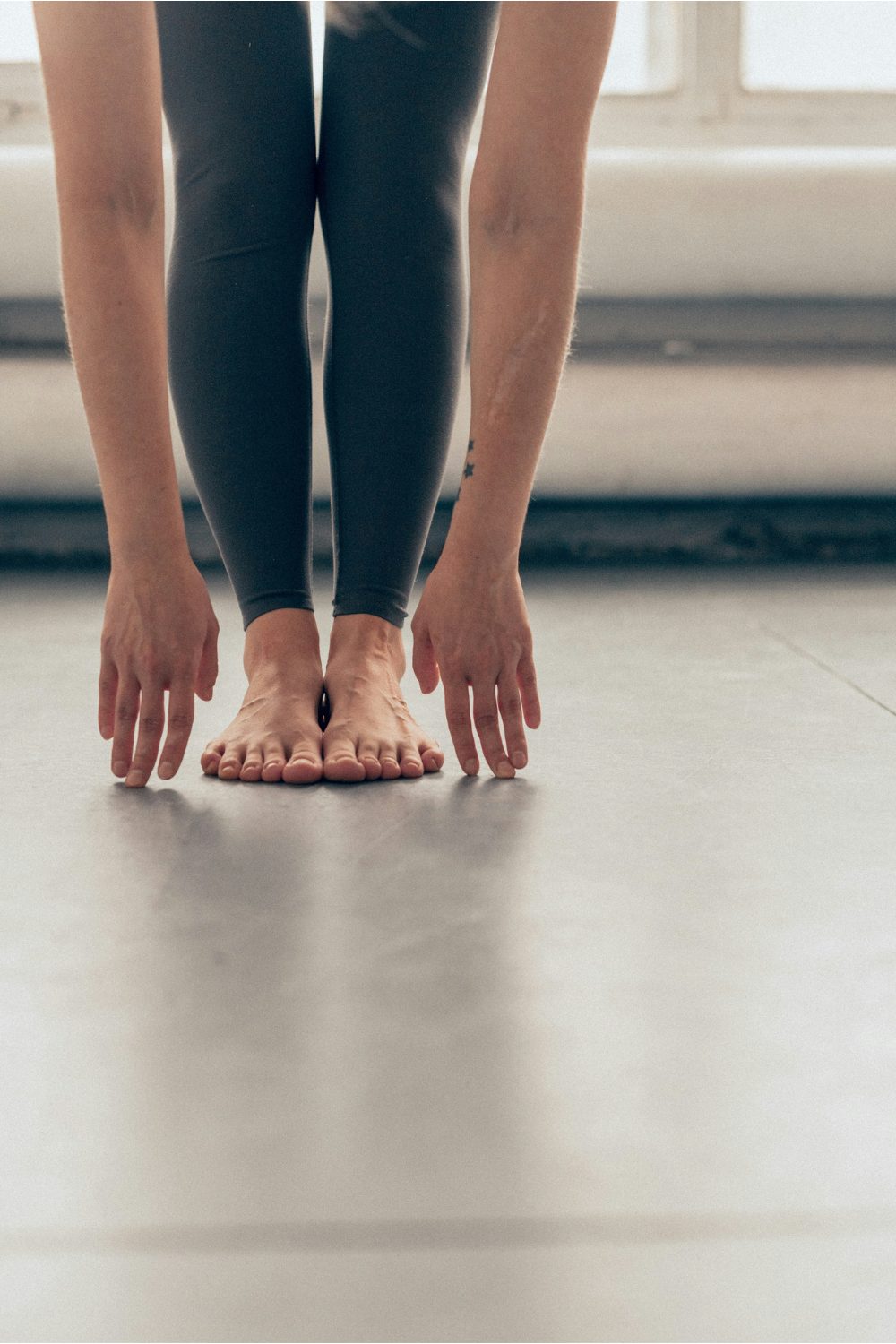 Arms and legs of a white person in black leggings stretching