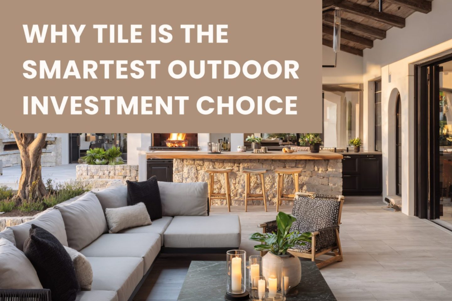 Outdoor area with wooden floor, kitchen island with tiled walls, grey sofa and stone coffee table holding candles