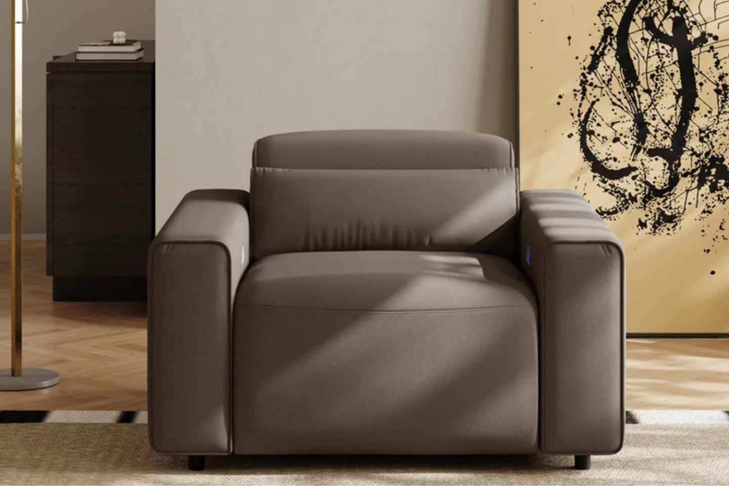 Brown armchair on beige rug next to gold lamp and in front of black and gold canvas propped against white wall