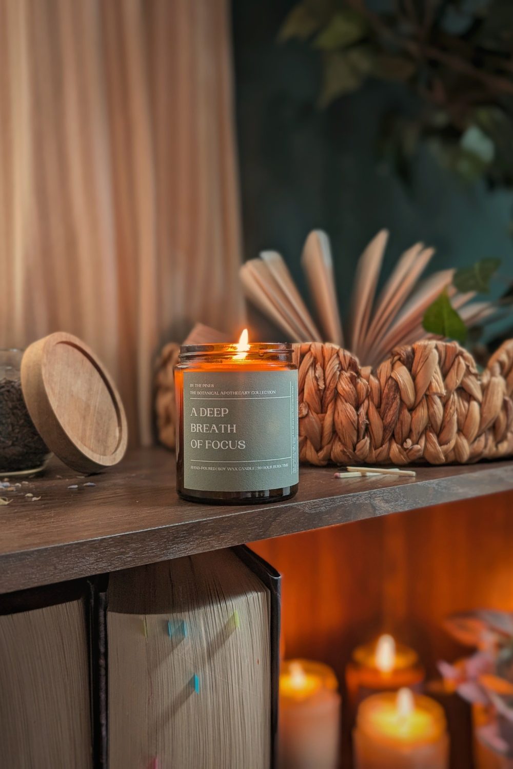 Lit candle on shelf next to woven storage basket and books