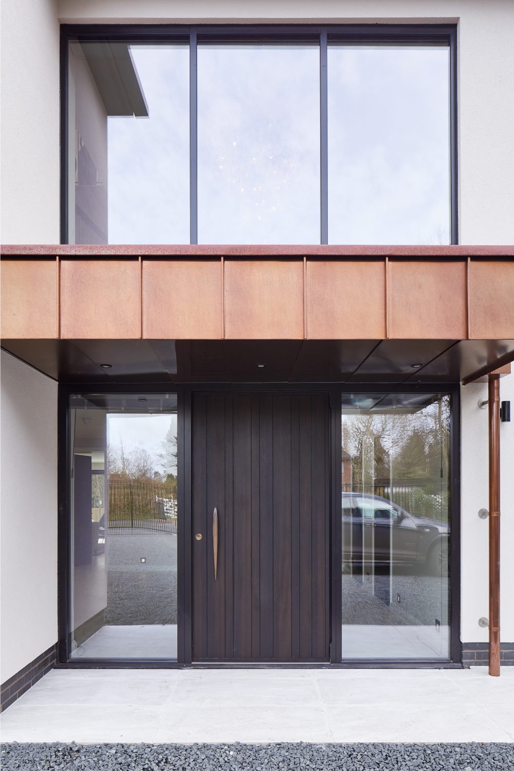 Front of white modern house with glass panels and dark wood door