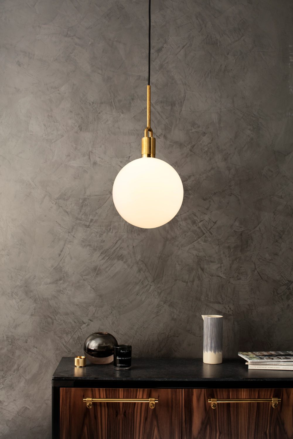 Hanging pendant light above a black cabinet with wooden doors against grey wall