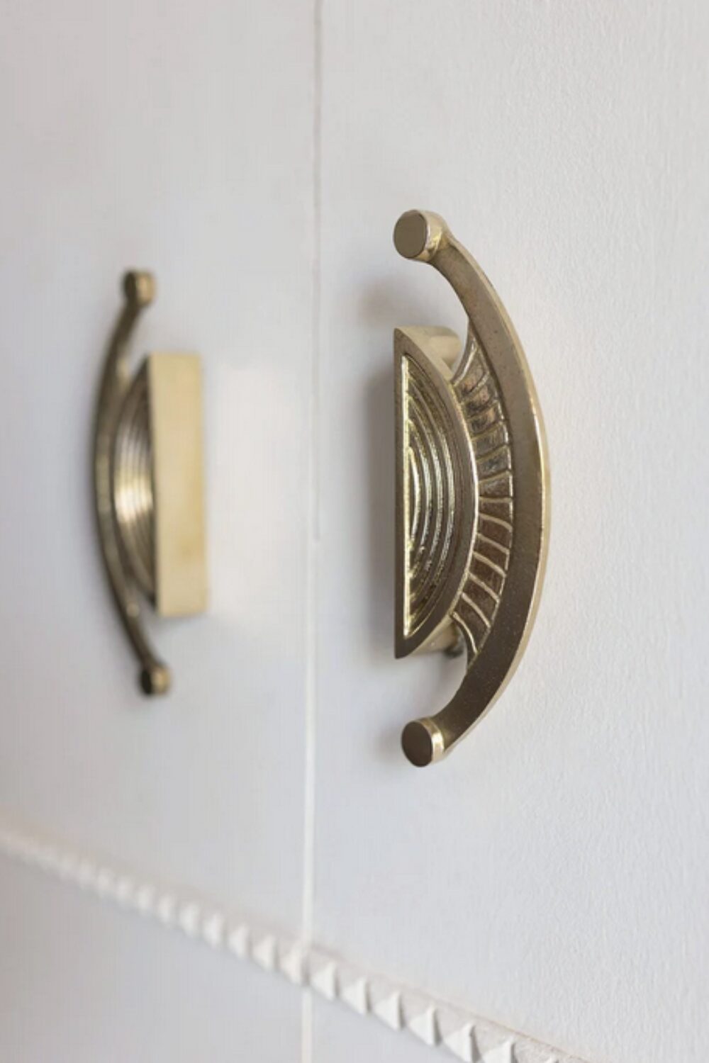 White cupboard with two semi-circular sculptural brass handles