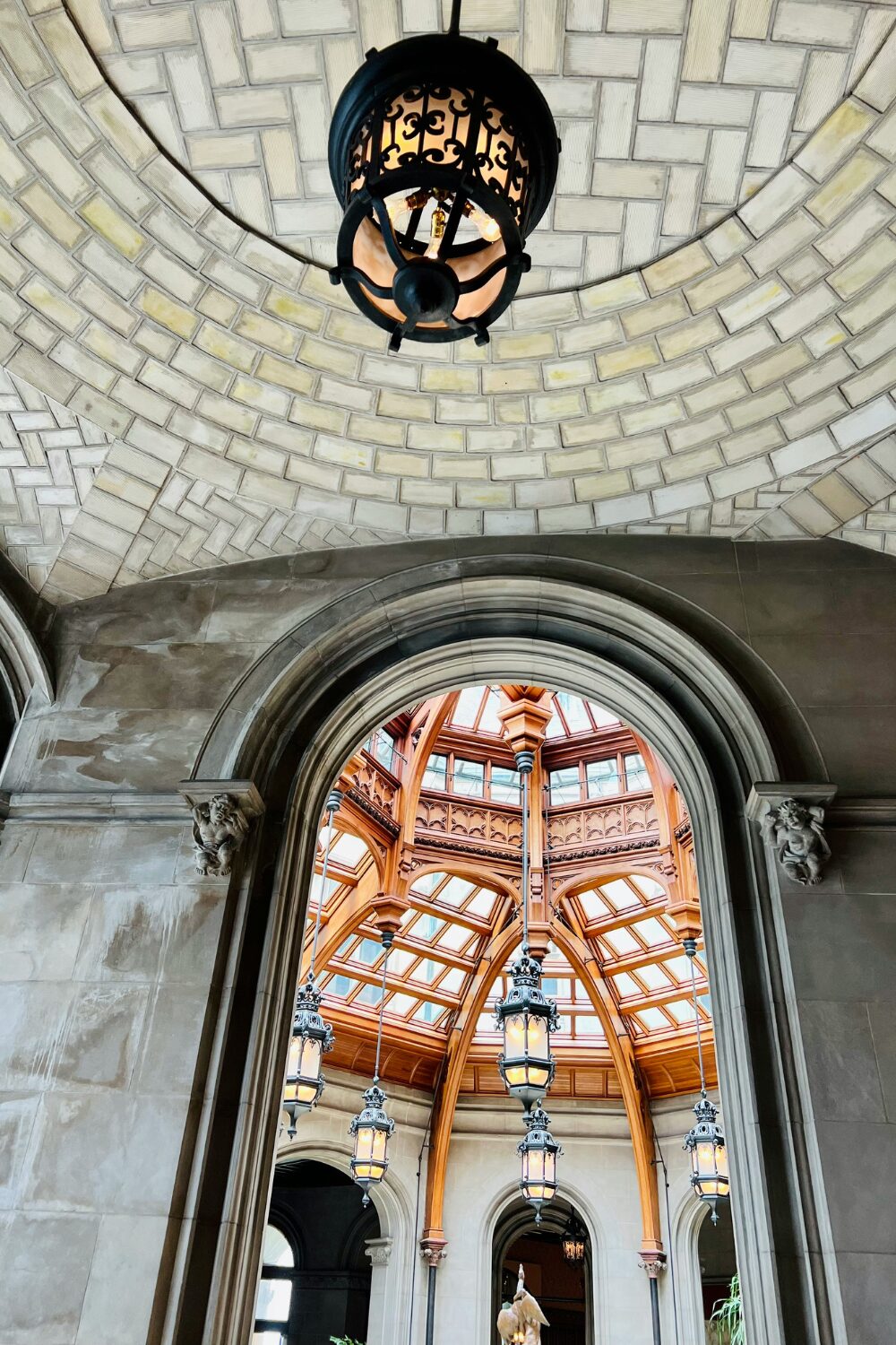 View of grand wooden and glass roof through stone arch