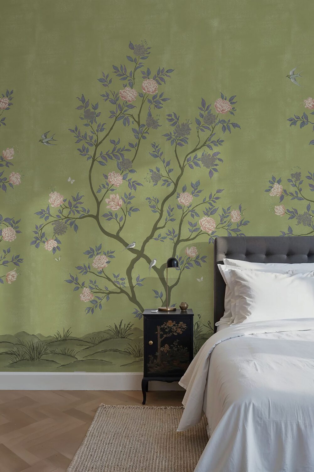 Bedroom with green mural wallpaper with tree design, grey bed and black cabinet