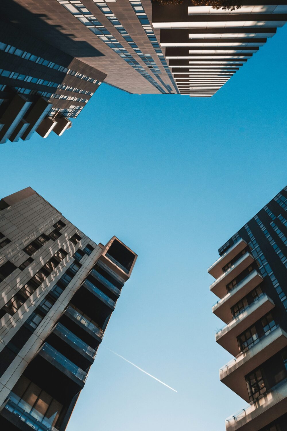 Ground-level view of four tall flat buildings against blue sky