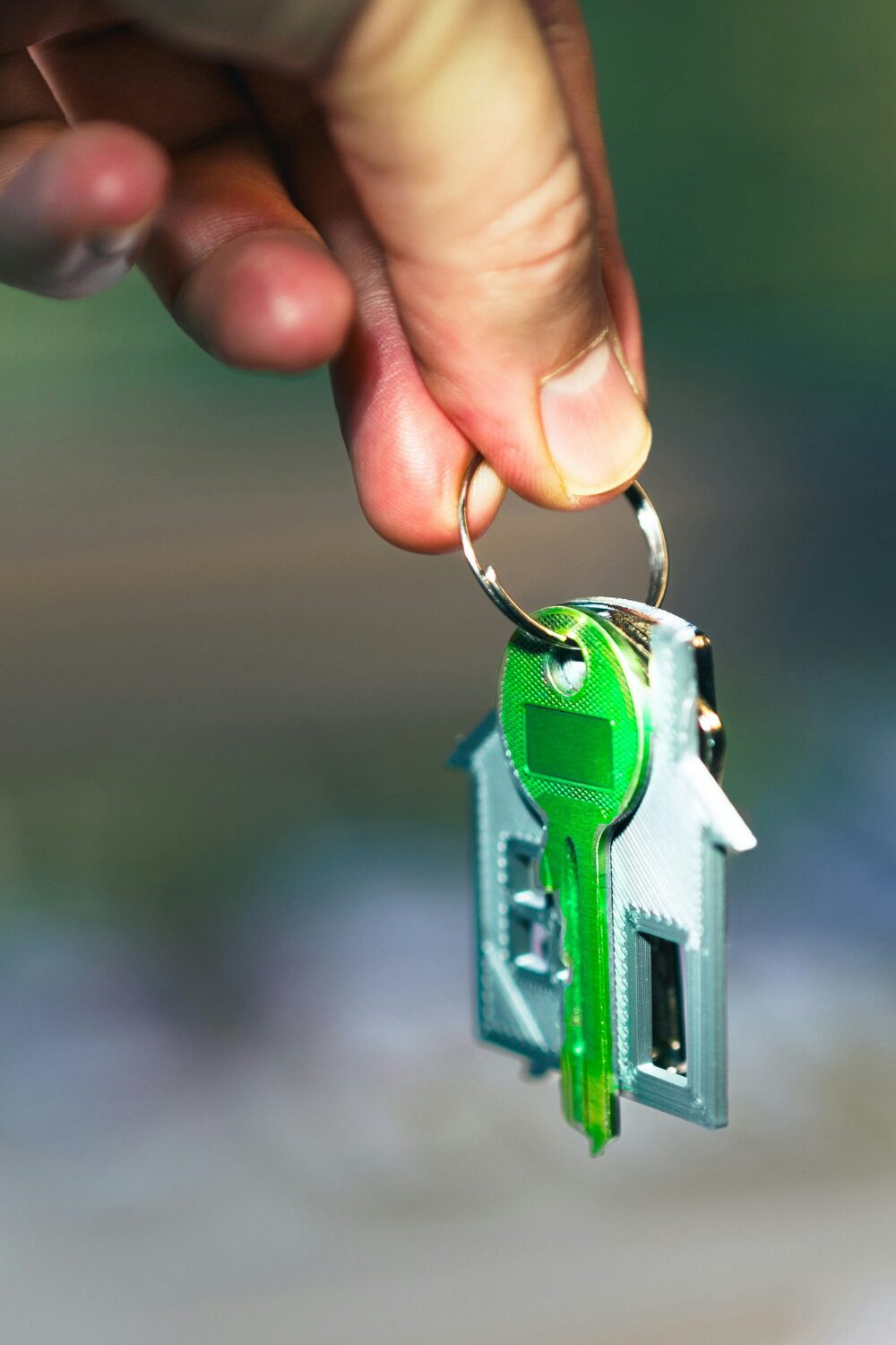 Hand holding keyring with green key and house keyring