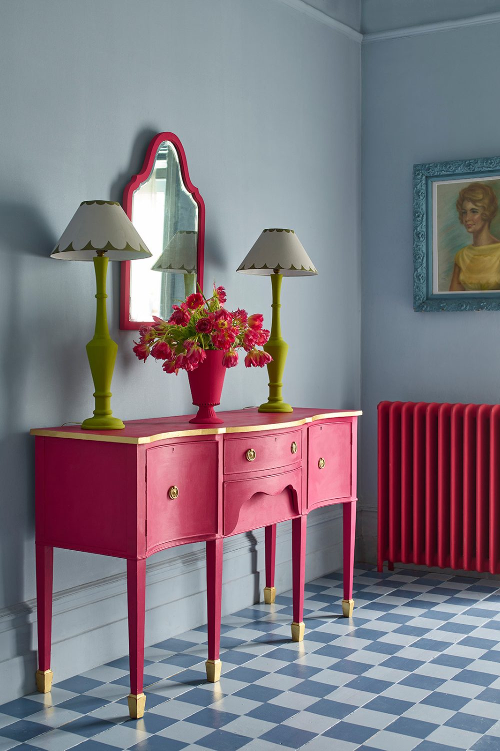 Bright pink sideboard and radiator in blue room with chequered floor