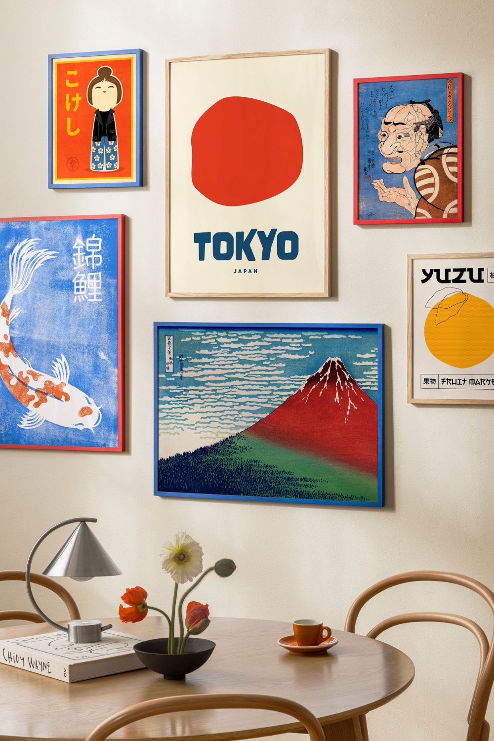 Gallery wall of colourful Japanese prints above a wooden table and chairs