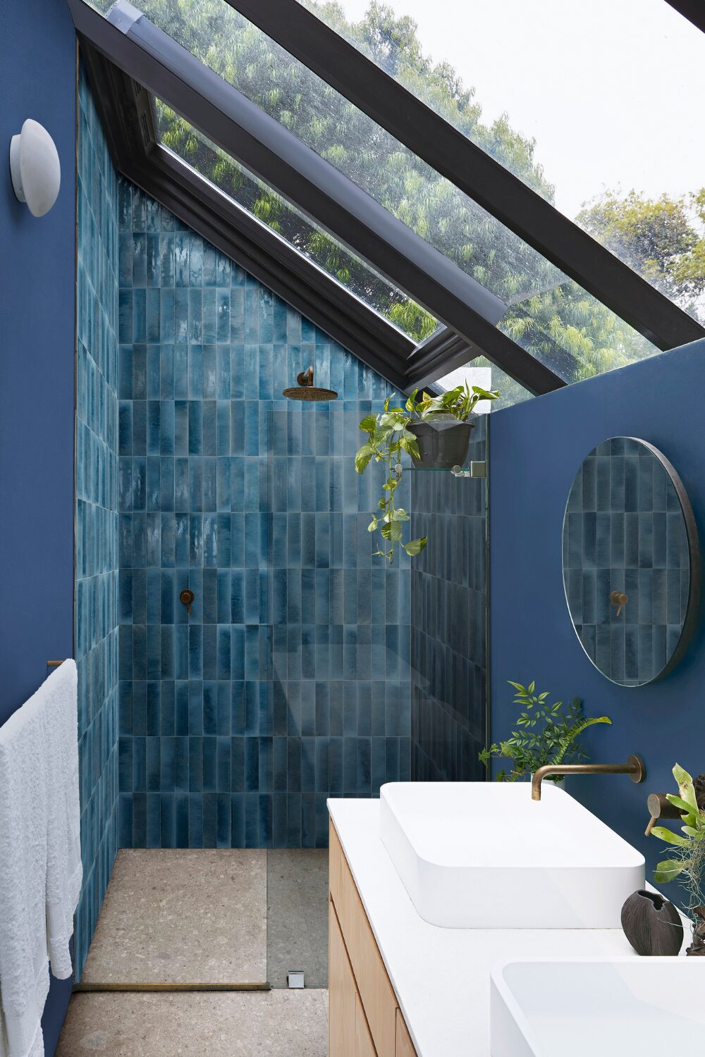 Blue-tiled shower in blue bathroom with sloping glass roof