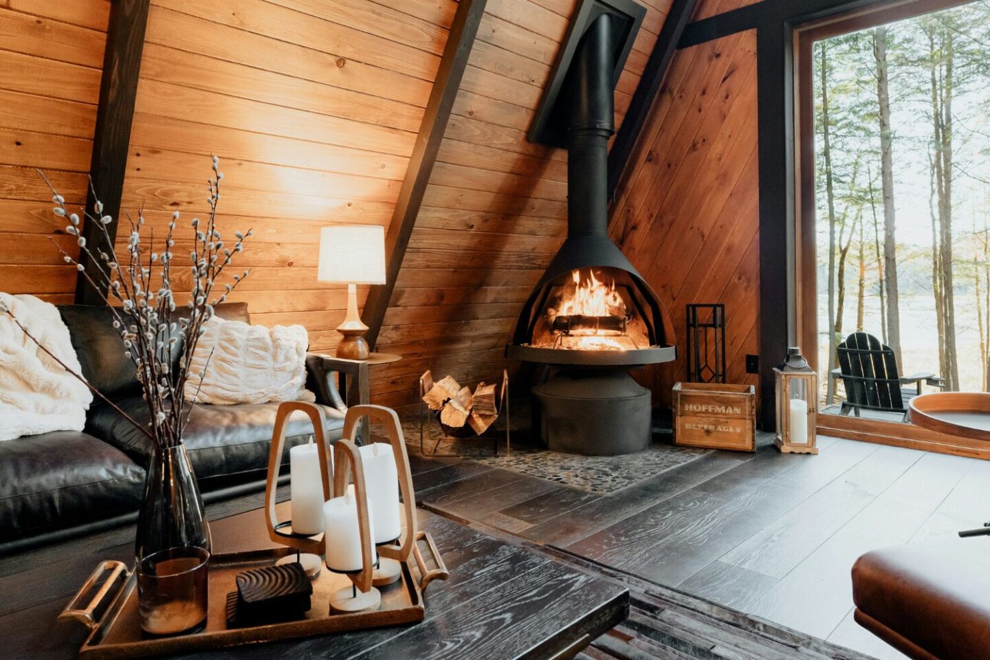 Wooden cabin with brown sofa, dark wood coffee table, log burner and forest view