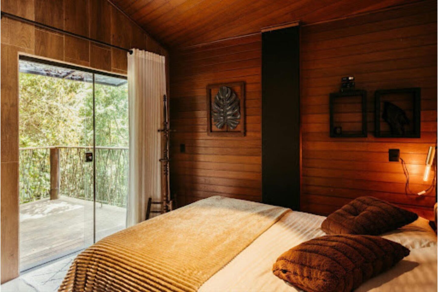 Bedroom in log cabin with glass doors opening to balcony with firest view