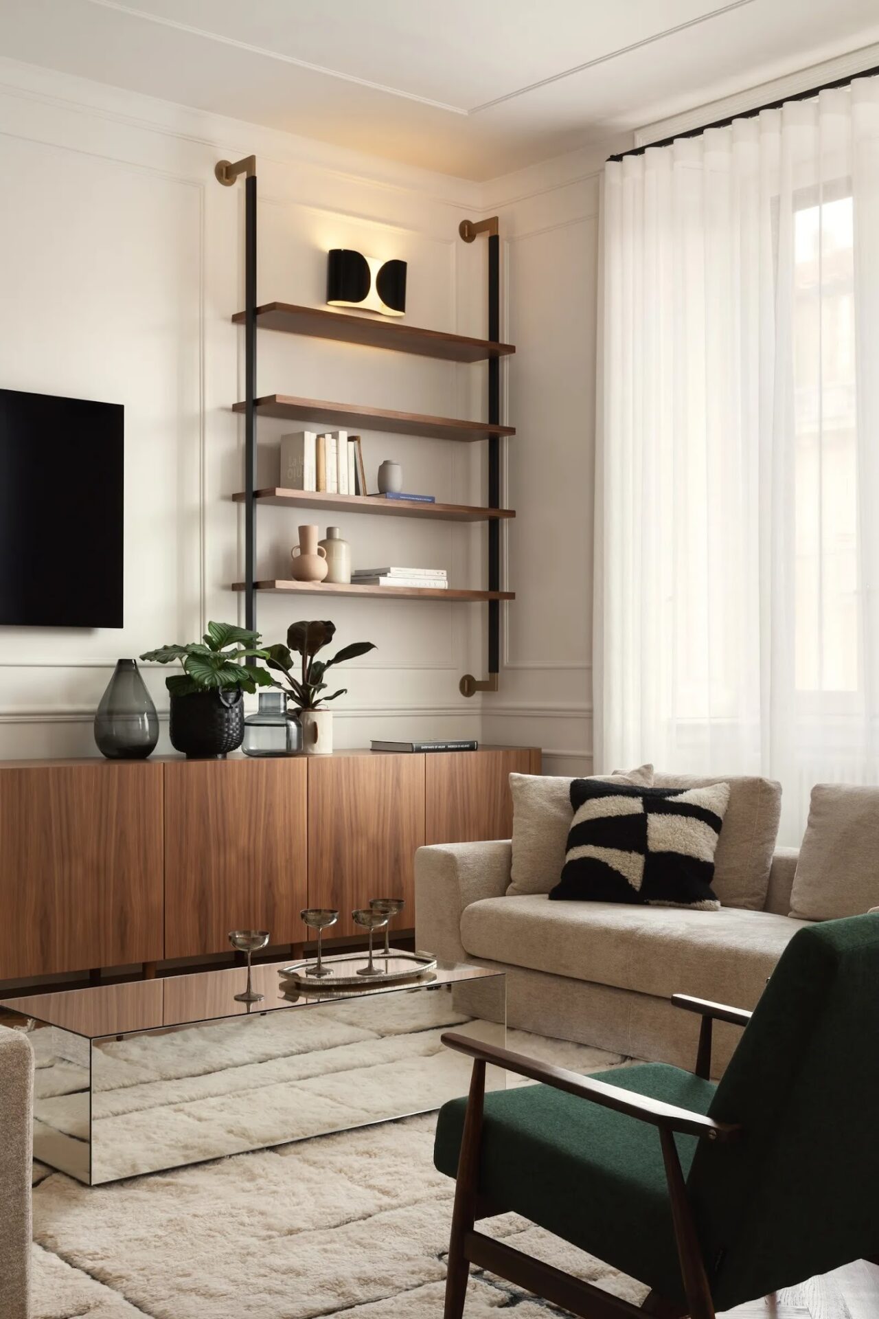 Simple, clean living room with cream walls, modern wall shelves, and low cupboards, tv on the wall, beige sofa, off white fluffy rug and glass cube coffee table.
