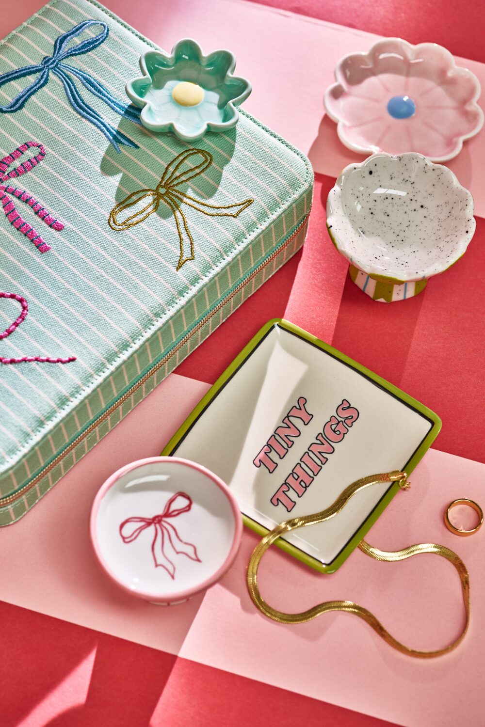 Ceramic trinket dishes and gold ring & necklace on pink surface