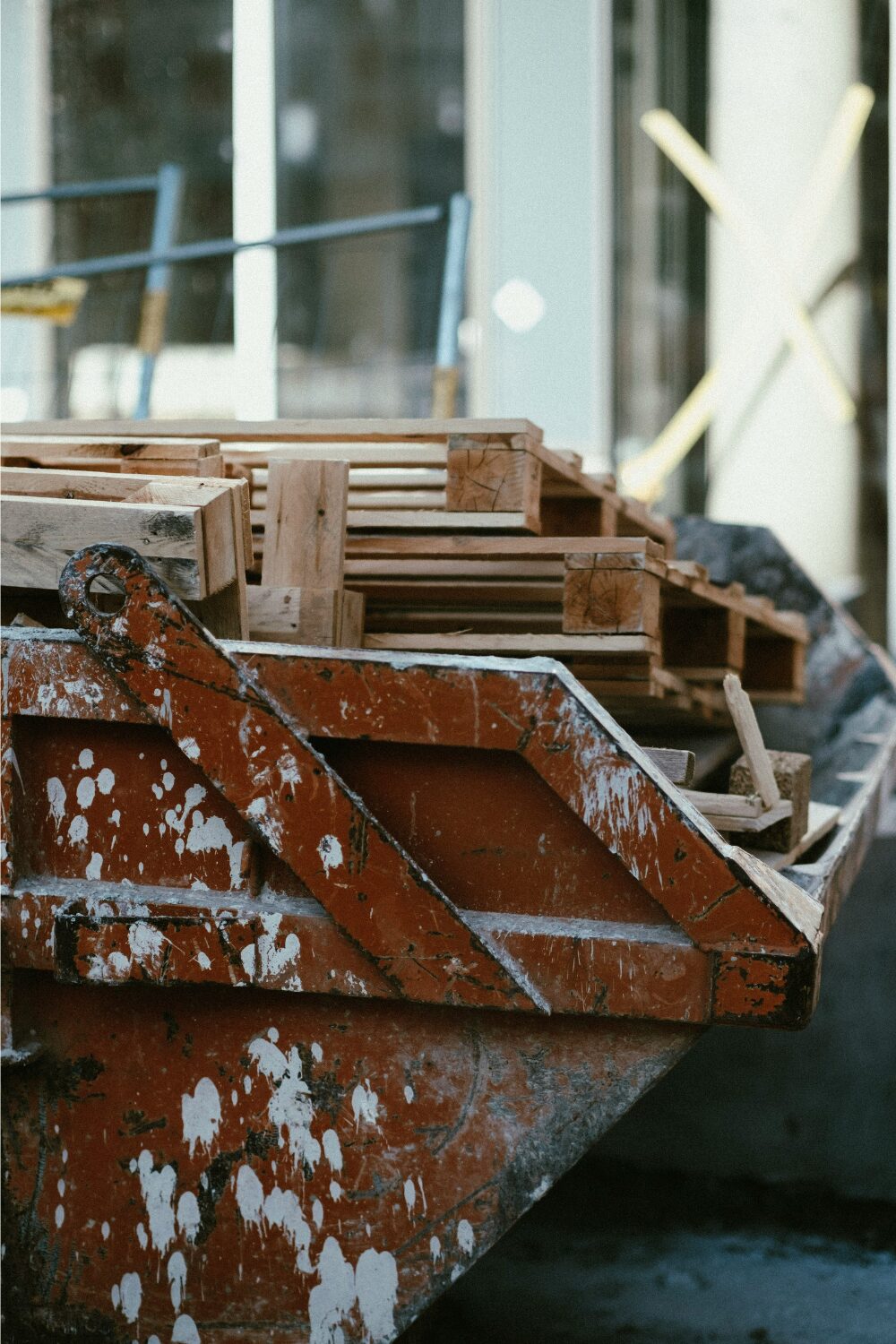 Red skip spattered with white paint holding wood pieces