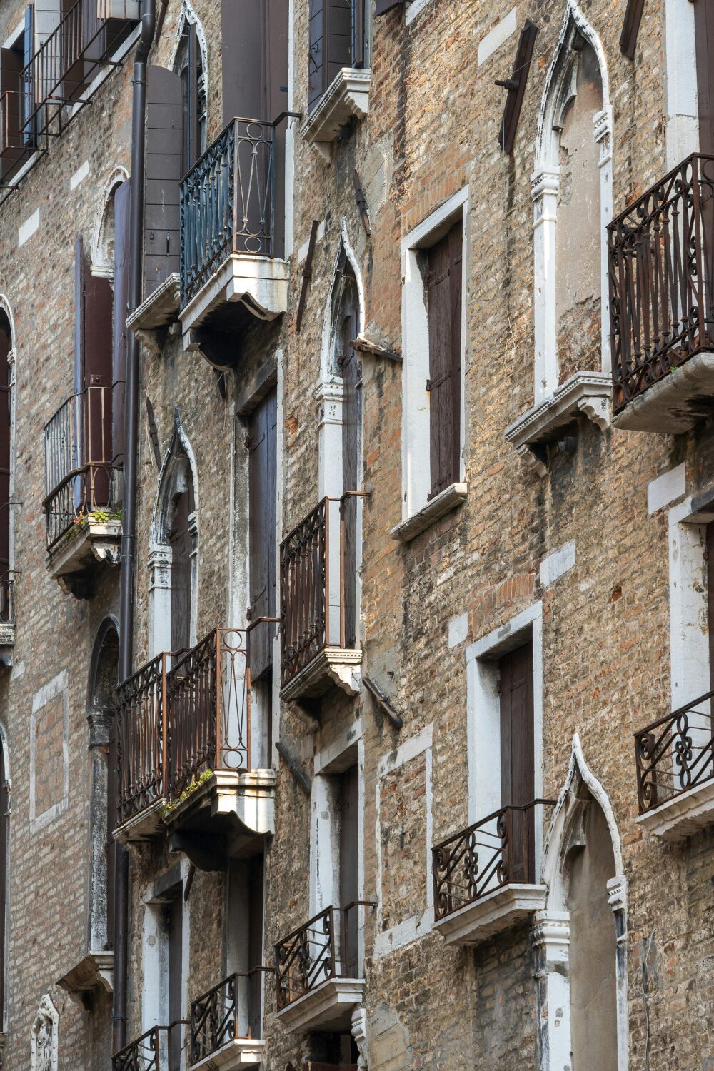 Exterior of brick building with many ornate windows and metal Juliet balconies