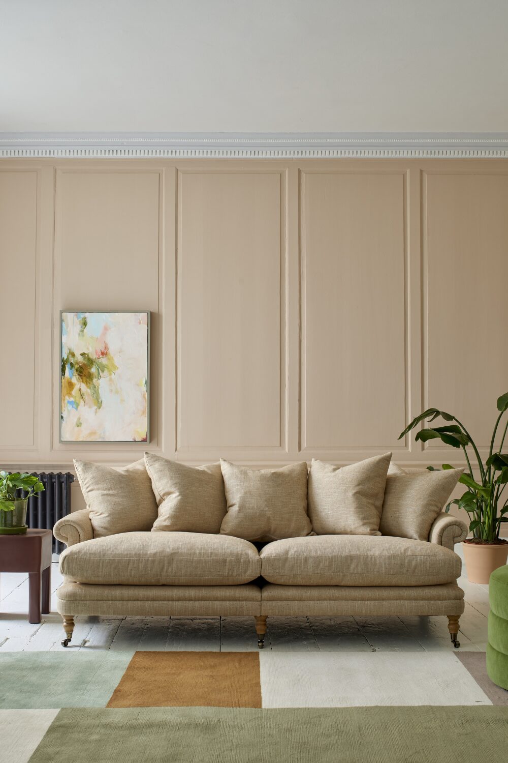 White sofa and green & white rug in white wood-panelled living room