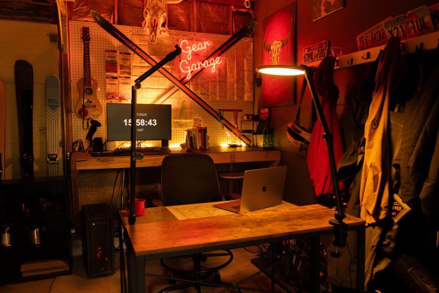 Wooden desk in converted garage with coat rack, neon sign, guitar and skateboards